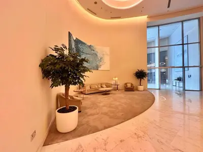 a large living room with a potted tree in the middle at Luxury 2BR with Full Burj Khalifa View in Dubai