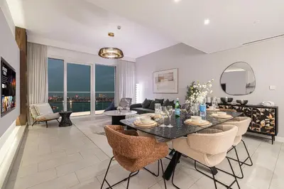a living room with a table and chairs and a couch at Luxurious 4BR La Vie JBR Private Beach Pool Panoramic Sea and Dubai Eye Views Drone Show Perfect for Family and Friends in Dubai