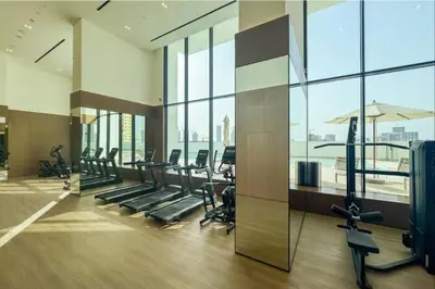 a gym with treadmills and ellipticals and windows at Vacationer l Contemporary 1 Bed l City Views l near Circle Mall in Dubai