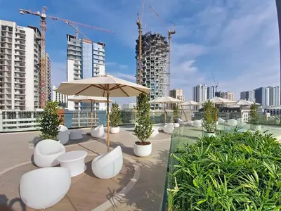 a patio with white chairs and an umbrella and buildings at Vacationer l Modern 1 Bed l Private Pool l Community Views in Dubai