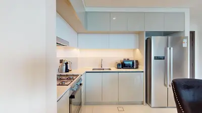 a kitchen with white cabinets and a stainless steel refrigerator at Vacationer l Classic 2 Bedroom l Marina Views l Private Beach in Dubai