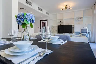 a dining table with a vase of blue flowers and wine glasses at Vacationer l Upgraded Modern 2 Bed l Downtown l Near Dubai Mall in Dubai