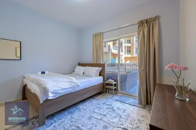 a bedroom with a bed and a large window at Modern 1BR Apartment in JVC Pool Gym Near Circle Mall in Dubai