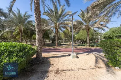 a street sign in a park with palm trees at Modern 1BR Apartment in JVC Pool Gym Near Circle Mall in Dubai