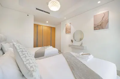 a white bedroom with two beds and a mirror at Highest Infinity Pool - Paramount Midtown Hotel & Luxury Apartments Burj Khalifa view & Partial Fountain View in Dubai