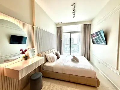 a bedroom with a bed and a desk and a window at Luxury 2BR Downtown Apartment - Canal & City Views in Dubai