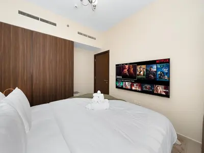 a bedroom with a white bed with a tv on the wall at Charming & Cozy 1BR Burj Khalifa Skyline View in Dubai