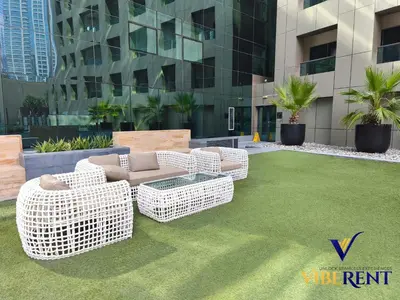 two wicker chairs and a couch on a lawn at Business Bay Retreat,Views & Vibes,10 min to Burj in Dubai