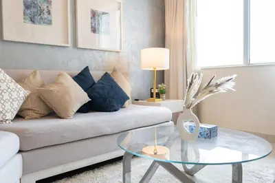 a living room with a couch and a glass table at Damac Maison Downtown Dubai Luxury 1BR Walk to Dubai Mall in Dubai
