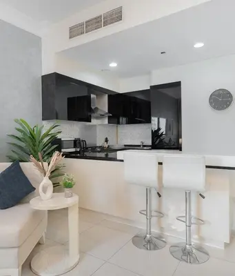 a living room with a couch and a kitchen at Damac Maison Downtown Dubai Luxury 1BR Walk to Dubai Mall in Dubai
