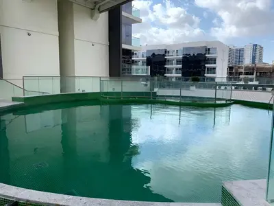 a large pool of green water in front of a building at HAVN - 1 bedroom in The Wings, Arjan in Dubai