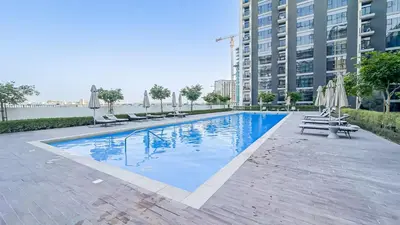 a large swimming pool with chairs and umbrellas at HAVN - Cozy 1 bedroom in Golfville in Dubai