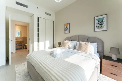a bedroom with a large bed with a white blanket at HAVN - Cozy 1 bedroom in Golfville in Dubai