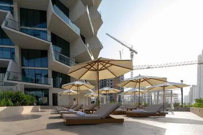 a row of lounge chairs with umbrellas in front of a building at Binghatti Phantom 1BR Luxe Suite with Private Pool in Dubai