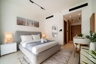 a bedroom with a large bed and a table at Beautifully Furnished Studio in Binghatti Azure in Dubai