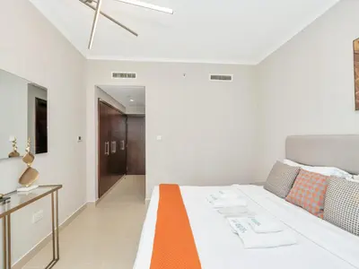 a bedroom with a bed with an orange and white blanket at Skyline Upscale 2 Bedroom Apartment I Steps to Burj Khalifa Dubai Fountain Dubai Mall I Mesmerizing Views I Free Gym, Pool, Parking & Wi-Fi in Dubai