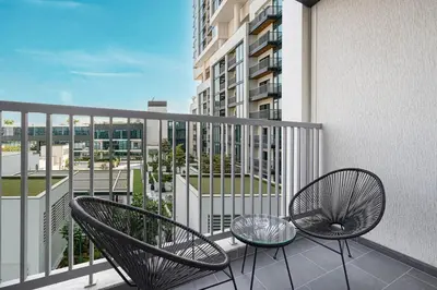 two chairs and a glass table on a balcony at Modern 2 Bedroom Apartment in Sobha Hartland in Dubai