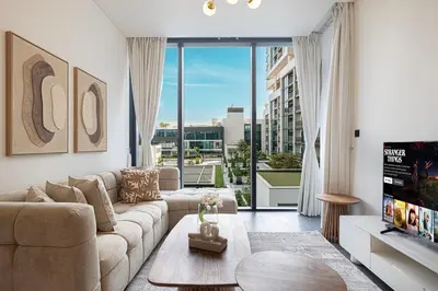 a living room with a couch and a large window at Modern 2 Bedroom Apartment in Sobha Hartland in Dubai