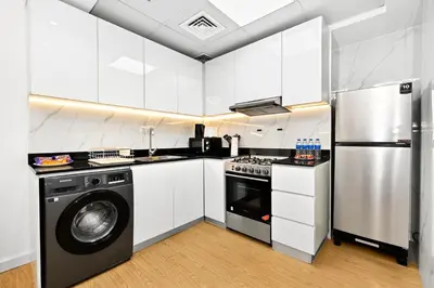 a kitchen with white cabinets and a washer and dryer at Chic 1BR Dubai Marina, 5 Min Walk JBR Beach, Metro in Dubai