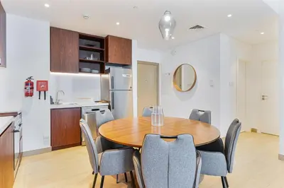 a kitchen and dining room with a wooden table and chairs at Sunny & Stylish 1Bed 7-Min Walk to the Beach! in Dubai