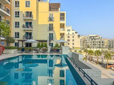 a swimming pool in front of a building at Sunny & Stylish 1Bed 7-Min Walk to the Beach! in Dubai