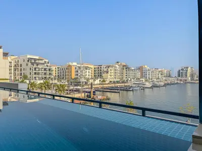 a swimming pool next to a body of water with buildings at Sunny & Stylish 1Bed 7-Min Walk to the Beach! in Dubai