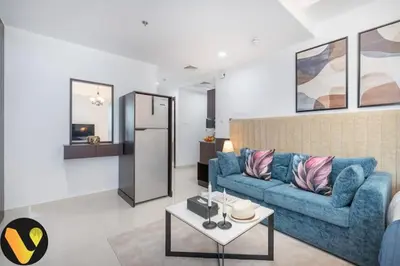 a living room with a blue couch and a table at Vogue Business Bay Court Tower close to Downtown Burj Khalifa and Dubai Mall, Studio Apartment with Canal view in Dubai