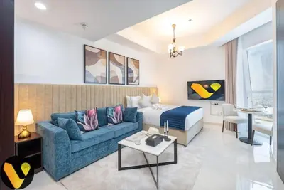 a hotel room with a bed and a blue couch at Vogue Business Bay Court Tower close to Downtown Burj Khalifa and Dubai Mall, Studio Apartment with Canal view in Dubai