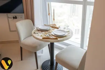 a table with two chairs and a table with plates at Vogue Business Bay Court Tower close to Downtown Burj Khalifa and Dubai Mall, Studio Apartment with Canal view in Dubai