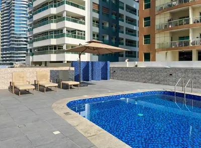 a swimming pool with an umbrella next to a building at Brand New Two Bedrooms Apartment With Amazing Marina View in Dubai