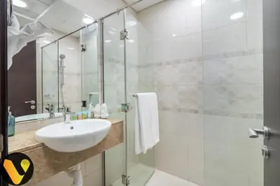a white bathroom with a sink and a shower at Vogue Business Bay Court Tower close to Downtown Burj Khalifa and Dubai Mall, Studio Apartment with City view in Dubai