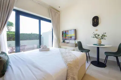 a bedroom with a bed and a table and a window at Silk Valley - Luxury St with Pool Access & Balcony | 10 Min to Downtown in Dubai