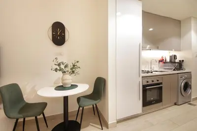 a kitchen with a table and chairs and a clock at Silk Valley - Luxury St with Pool Access & Balcony | 10 Min to Downtown in Dubai