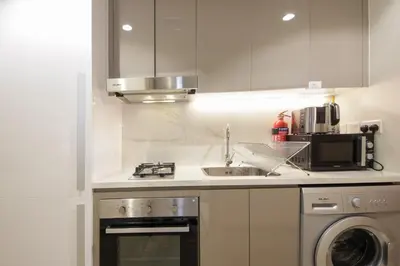 a white kitchen with a sink and a microwave at Silk Valley - Luxury St with Pool Access & Balcony | 10 Min to Downtown in Dubai