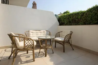 three chairs and a table on a patio at Silk Valley - Luxury St with Pool Access & Balcony | 10 Min to Downtown in Dubai