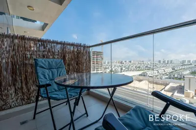 a glass table and chairs on a balcony with a view at Bespoke Holiday Homes - Cozy Modern Studio in Samia by Azizi in Dubai