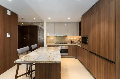 a kitchen with wooden cabinets and a marble counter top at Imperial Avenue, Downtown Dubai - The Mint Stay in Dubai