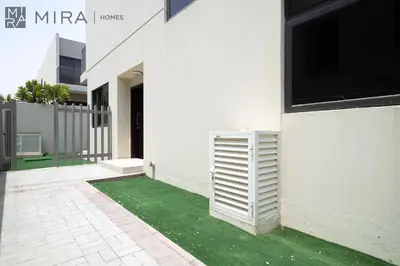 a white house with a green lawn next to a building at Mira Holiday Homes - Spacious 3BDR Villa Stylish & Modern Comfort in Dubai