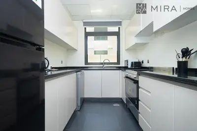 a white kitchen with white cabinets and a window at Mira Holiday Homes - Spacious 3BDR Villa Stylish & Modern Comfort in Dubai