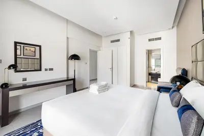 a white bedroom with a bed and a fireplace at Luxury Unit High Floor Damac Majestine in Dubai