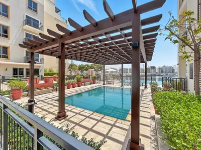 a pergola over a swimming pool in a building at La Mer Le Pont 1 Bedroom Beachside Apartment in Dubai