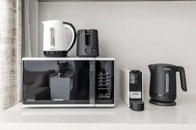 a microwave sitting on top of a counter with other appliances at La Mer Le Pont 1 Bedroom Beachside Apartment in Dubai