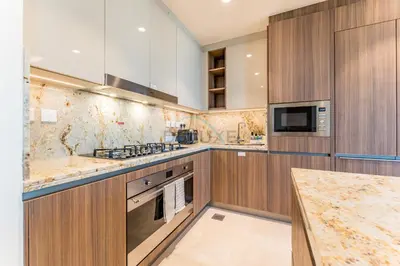 a kitchen with marble counter tops and wooden cabinets at Walking Distance to Dubai Mall and Burj Khalifa, Easy Access to Dubai Marina, JBR Beach and Palm Jumeirah - Imperial Avenue, Downtown Dubai in Dubai