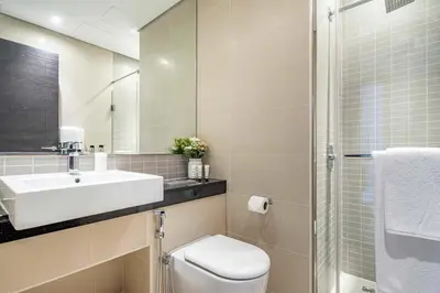 a bathroom with a sink and a toilet and a mirror at Frank Porter - Silverene Towers in Dubai