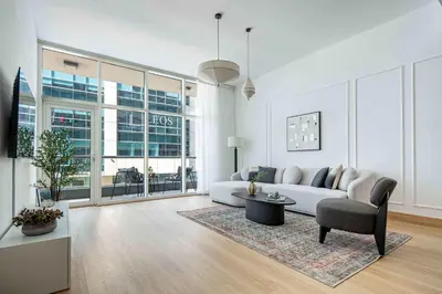 a white living room with a couch and a chair at Frank Porter - Bay Square in Dubai