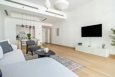 a living room with a couch and a tv on a wall at Frank Porter - Bay Square in Dubai