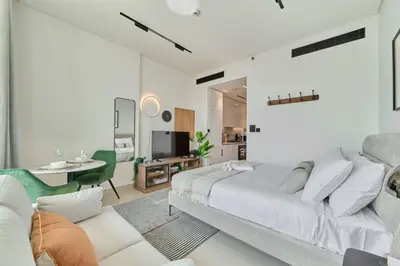 a white bedroom with a bed and a living room at Modern Studio at Binghatti Azure In Heart of JVC in Dubai