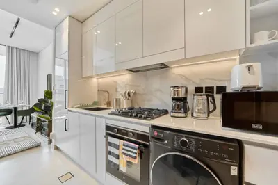 a kitchen with a stove and a washer and dryer at Modern Studio at Binghatti Azure In Heart of JVC in Dubai