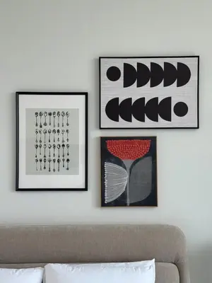 three framed pictures on a white wall with a couch at Modern Studio at Binghatti Azure In Heart of JVC in Dubai