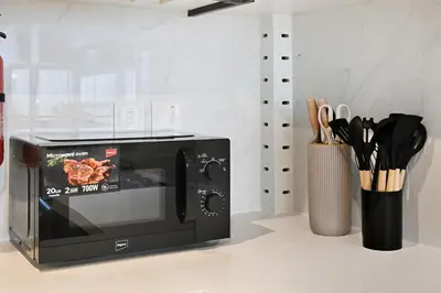 a microwave on a counter next to a vase with utensils at Skyline 1 Residence 2204 in Dubai